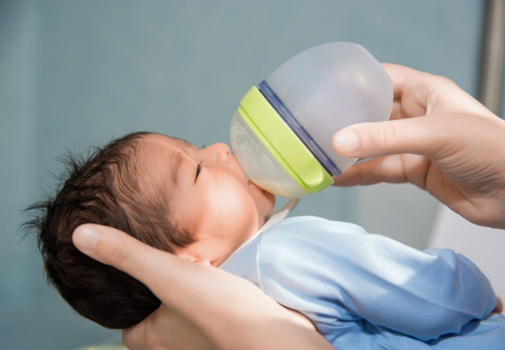 newborn baby is being fed from small bottle at the hospital